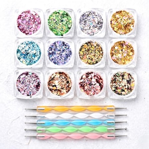 May include: An assortment of colorful glitter in small, clear square containers. Below are four double-ended dotting tools with yellow, white, blue, and pink handles. The glitter colors include pink, green, silver, gold, teal, purple, and brown.