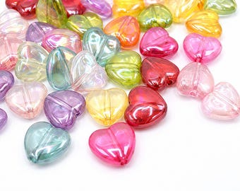 May include: A collection of translucent heart-shaped beads in various colors including pink, yellow, green, purple, and blue. Each bead features a smooth, glossy finish with an iridescent sheen and a vertical hole running through the center.