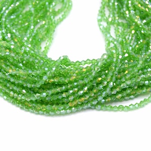 May include: A strand of green faceted glass beads. The beads are small and have a slight iridescent sheen.