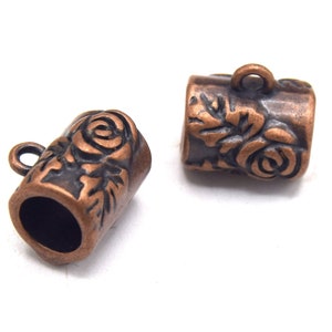 Op de afbeelding: Twee koperkleurige metalen koord eindkappen met een rozenontwerp. Elke dop heeft een kleine lus om aan een koord te bevestigen.