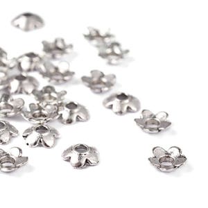 Peut inclure: Une dispersion de capsules de perles en forme de fleur de couleur argentée. Les capsules ont un petit trou au centre pour le perlage.