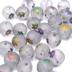 Peut inclure: Un ensemble de perles en verre dépoli, chacune ornée d'un motif de feuille d'érable colorée. Les perles rondes présentent une texture subtile et tourbillonnante. Les motifs de feuilles d'érable présentent un dégradé de couleurs, dont le vert, l'or et le violet.