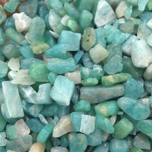 Può includere: Primo piano di una collezione di piccole pietre lisce di colore acquamarina. Le pietre sono di varie forme e dimensioni e sono tutte levigate e lucidate.