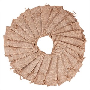 May include: A set of 30 small, brown burlap drawstring bags arranged in a circle. The bags are made of natural burlap fabric and have a rustic, earthy look.