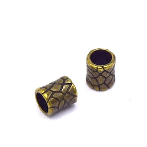 May include: Two gold-toned metal end caps with a textured, scaly design. The end caps are about 1 inch in diameter.