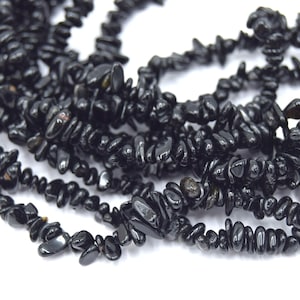 Peut inclure: Un brin de perles en obsidienne noire. Les perles sont de forme irrégulière et ont une finition brillante.