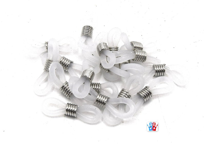May include: A pile of white plastic and silver eyeglass cord end tips. The tips are designed to attach to eyeglass cords or chains.