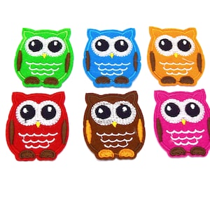 May include: Six felt owl appliques in different colors: green, blue, orange, red, brown, and pink. Each owl has white eyes, a white beak, and a white belly.