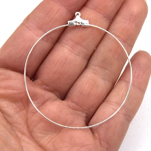 May include: Silver hoop earring with a jump ring closure. The hoop is approximately 2 inches in diameter.