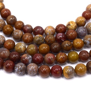 May include: Close-up of gemstone beads in a range of brown, red, and yellow hues. The spherical beads are polished to a high shine, displaying varied patterns. Suitable for crafting necklaces, bracelets, or other jewellery.