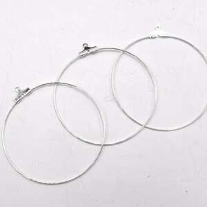 May include: Three silver hoop earrings with jump rings. The hoops are different sizes.