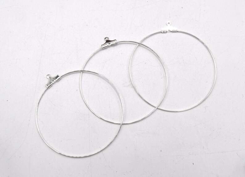 May include: Three silver hoop earrings with jump rings. The hoops are different sizes.