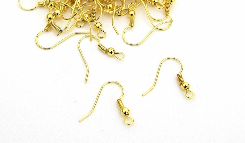 May include: A close-up of gold-toned earring hooks with a spring-loaded closure. The hooks are made of metal and have a smooth, polished finish.