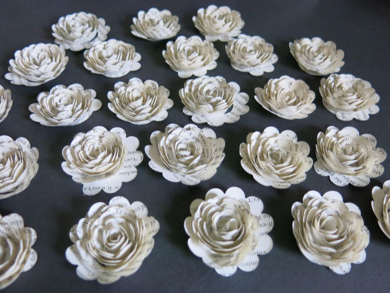 Peut inclure: Une collection de 20 fleurs en papier de couleur cr&egrave;me, chacune avec un design unique et superpos&eacute;. Les fleurs sont faites de pages de livres recycl&eacute;es et ont un aspect vintage.