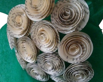 May include: A bouquet of paper flowers made from book pages. The flowers are tightly rolled, with visible text from the pages. The arrangement sits on a green background, creating a unique and literary aesthetic.