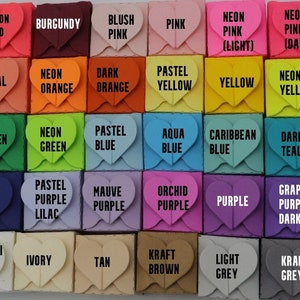 May include: A collection of small, heart-shaped boxes in various colors, including red, pink, yellow, blue, and green. Each box has a label with the color name, such as "Red," "Pink," and "Green." The boxes are arranged in a grid pattern.