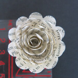 Peut inclure: Une fleur en papier blanche faite de pages de livre, avec du texte comprenant "Personal", "Hunter", "Mark", "Conic", "Digito", "America", "Plan", "was", "to", "work", "self", "have", "and", "in", "the", "outst", "am", "s", "rd", "I", "inte", "nosa", "fome", "cant", "arceful", "to", "w8142", "ks", "to", "ica", "a", "the", "nne",  "hand", "of", "the", "most", "important", "things", "in", "life", "are", "the", "people", "you", "love", "and", "the", "memories", "you", "make", "together".