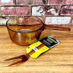 May include: A white ceramic mug with a black handle and the text "But First, Coffee" in a black, handwritten-style font. The mug is on a white surface.