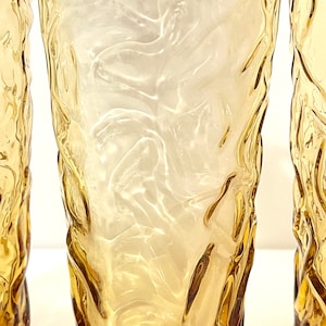 Op de afbeelding: Drie amber glazen met een getextureerd, golvend ontwerp. De glazen zijn helder en hebben een licht amberkleurige tint.