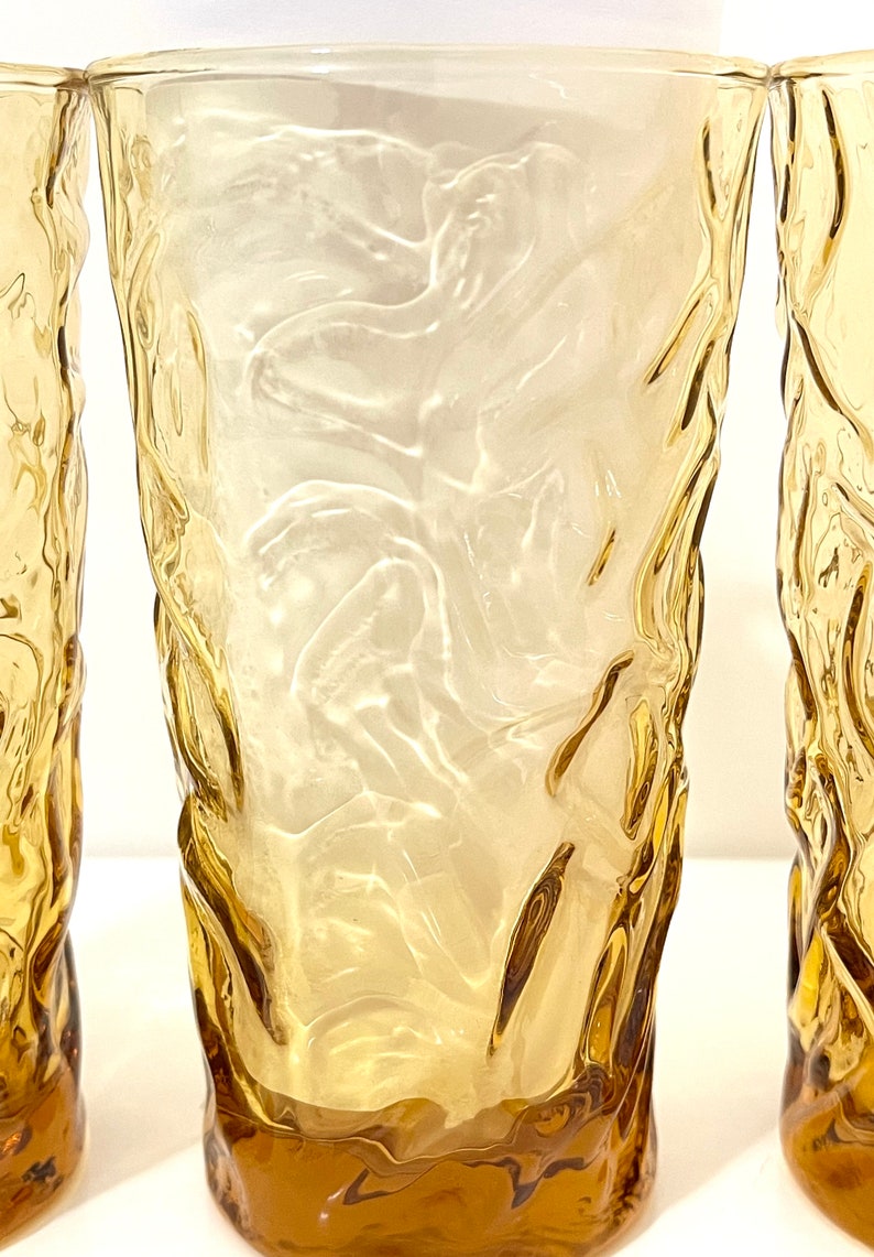 Op de afbeelding: Drie amber glazen met een getextureerd, golvend ontwerp. De glazen zijn helder en hebben een licht amberkleurige tint.