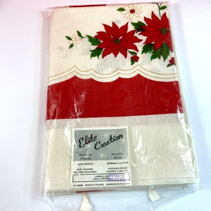 May include: A white tablecloth with a red and white border. The tablecloth features a red poinsettia design with green leaves and white flowers. The tablecloth is packaged in plastic and has a label that reads "Elite Creation" and includes information about the fabric content, care instructions, and size. The label also states "Made in Poland".