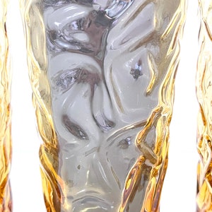 Op de afbeelding: Set van drie amberkleurige glazen met een getextureerd, geribbeld oppervlak. De glazen zijn helder en hebben een licht amberkleurige tint.