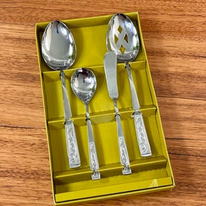 May include: A set of four silver-toned serving utensils in a green box. The set includes a slotted spoon, a butter knife, and two spoons.