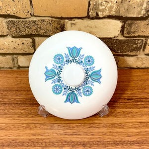 May include: White ceramic lid with a blue and green floral design. The design features stylized tulips and leaves.