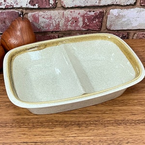 May include: A divided serving dish with a speckled white glaze and a brown rim. The dish is made of ceramic and has a rectangular shape.