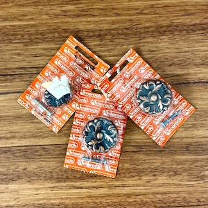 May include: Three antique-style cabinet knobs with a floral design. The knobs are packaged on orange and white cards with the brand name "Amerock" printed on them.