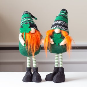 May include: Two green and white gnome figurines with red and orange hair. One gnome is holding a green shamrock with the text "Luck of the Irish".