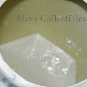 May include: The inside of a white ceramic pitcher with a blue and white swirl design. The pitcher is empty.