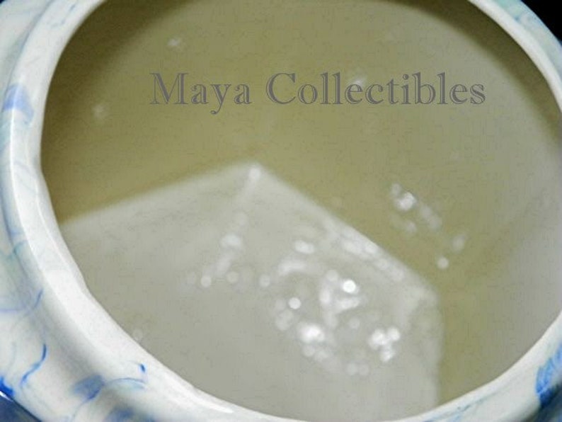 May include: The inside of a white ceramic pitcher with a blue and white swirl design. The pitcher is empty.