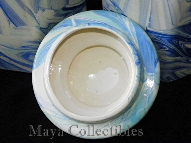 May include: A white ceramic lid with a blue and white marbled design. The lid is for a canister or jar.