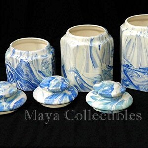 May include: Set of four blue and white ceramic canisters with lids. The canisters have a marbled design and are perfect for storing sugar, coffee, tea, or other kitchen staples.