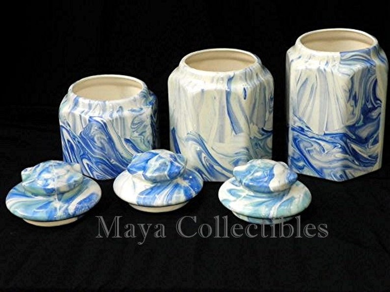 May include: Set of four blue and white ceramic canisters with lids. The canisters have a marbled design and are perfect for storing sugar, coffee, tea, or other kitchen staples.