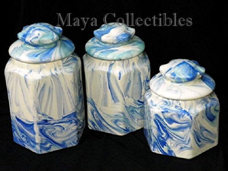 May include: Set of three blue and white ceramic canisters with octagonal shapes and lids. The canisters have a marbled design.