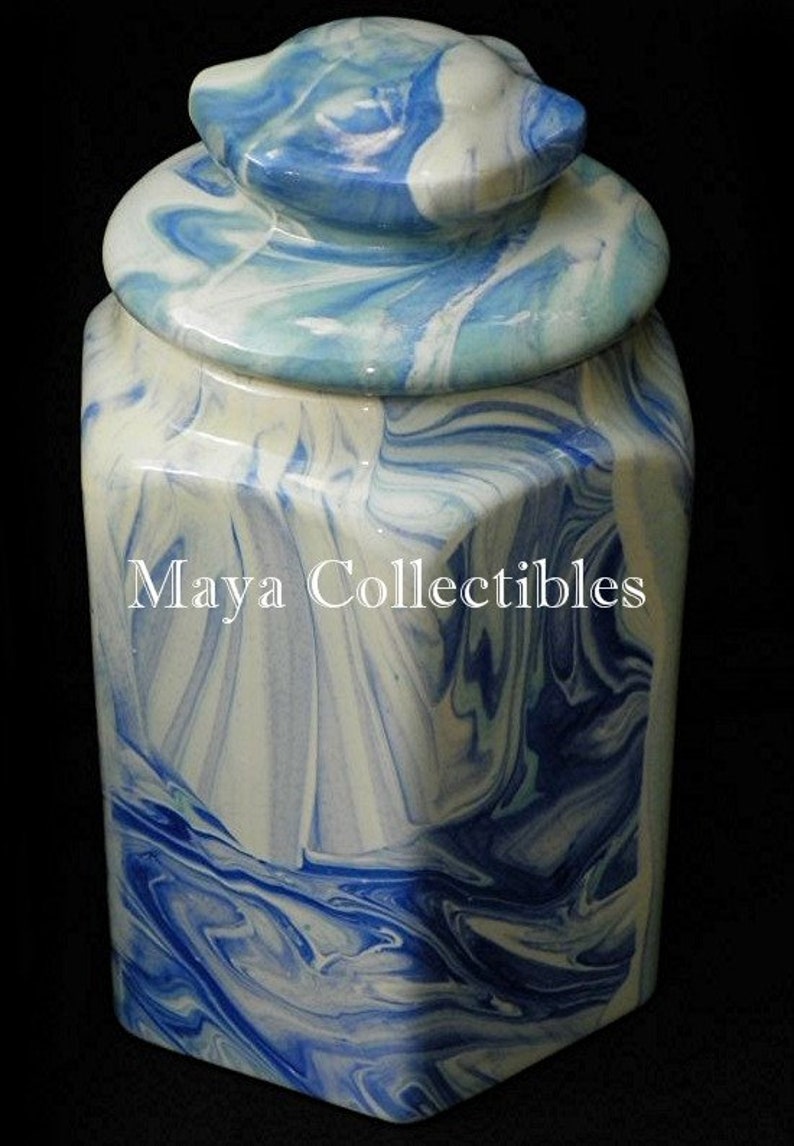 May include: A blue and white ceramic jar with a lid. The jar has a marbled design and a hexagonal shape. The lid is also marbled and has a rounded top.