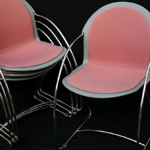 May include: Stack of modern chairs with pink seats and gray trim. The chairs have a curved, chrome-colored metal frame. The text "Maya's Collectibles" is visible at the bottom of the image.