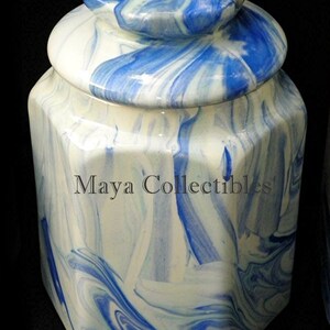 May include: A white and blue ceramic jar with a marbled design. The jar has a lid with a rounded top and a hexagonal base.