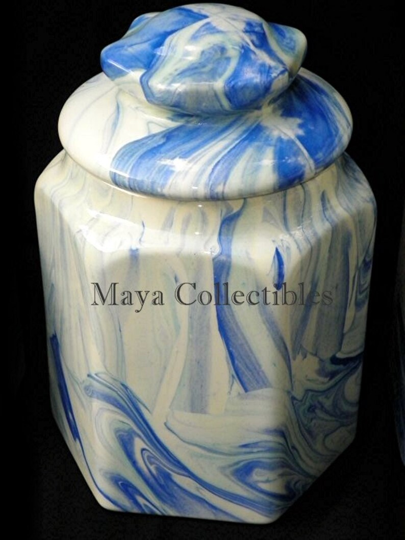 May include: A white and blue ceramic jar with a marbled design. The jar has a lid with a rounded top and a hexagonal base.