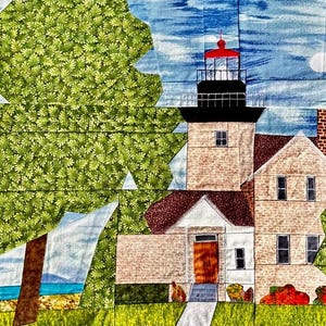 Könnte beinhalten: Ein Stoffkunstwerk, das einen Leuchtturm mit roter Spitze und schwarzem Laternenraum darstellt. Der Leuchtturm besteht aus beigefarbenen Ziegeln und ist mit einem Haus mit braunem Dach verbunden. Ein grüner Baum und blauer Himmel mit Mond sind im Hintergrund.