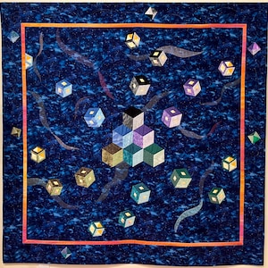 May include: A blue quilt with a geometric design of 3D cubes in shades of green, purple, and blue. The cubes are surrounded by smaller, scattered cubes in shades of yellow and white, all against a dark blue background.