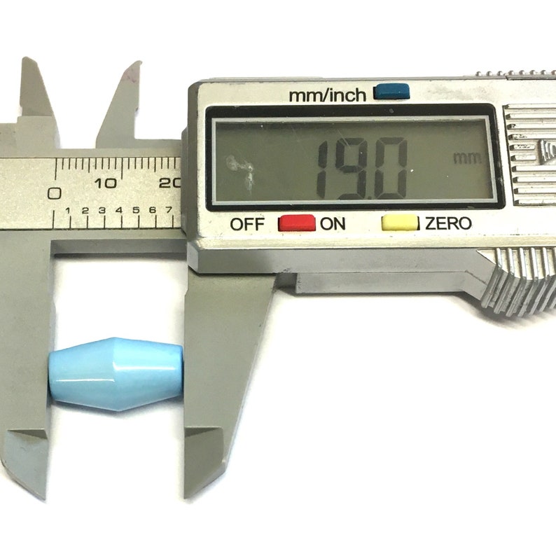 May include: A blue glass bead is measured with a digital caliper. The caliper reads 190 mm.