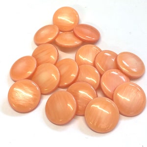 May include: A group of 18 peach-colored round buttons with a pearlescent finish.