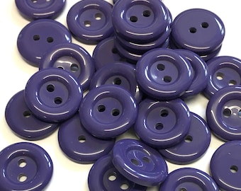 May include: A group of purple plastic buttons with two holes each. The buttons are shiny and have a smooth surface.