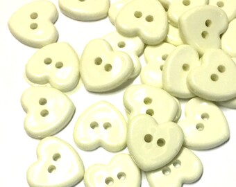 May include: A collection of off-white heart-shaped buttons with two holes each.