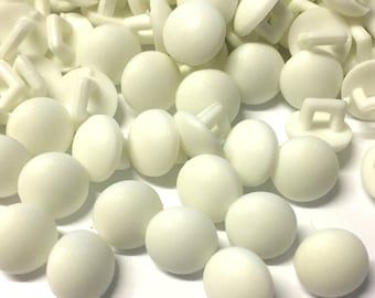 May include: A large group of white plastic buttons with a small loop on the back of each button.