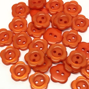 May include: A collection of 20 orange plastic flower-shaped buttons with two holes each.