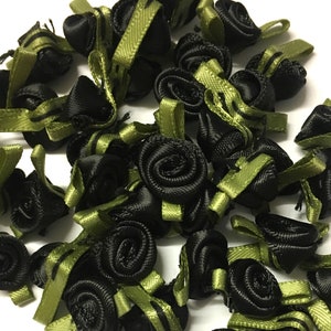 May include: A pile of black and green fabric rose embellishments. The roses are made of satin and have a green ribbon attached to the back.